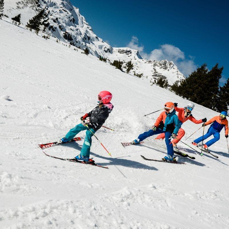 Group skiing downhill on snowy mountain slope during sunny winter day